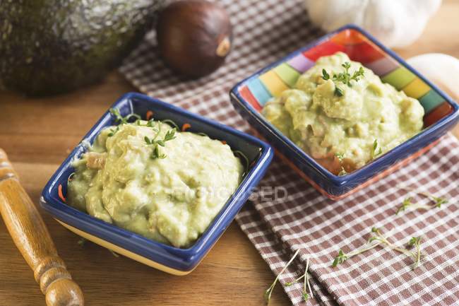 Guacamole in two dishes  over wooden surface with towels — Stock Photo