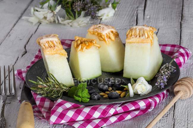 Vista de cerca de trozos de melón con menta, romero y arándanos - foto de stock