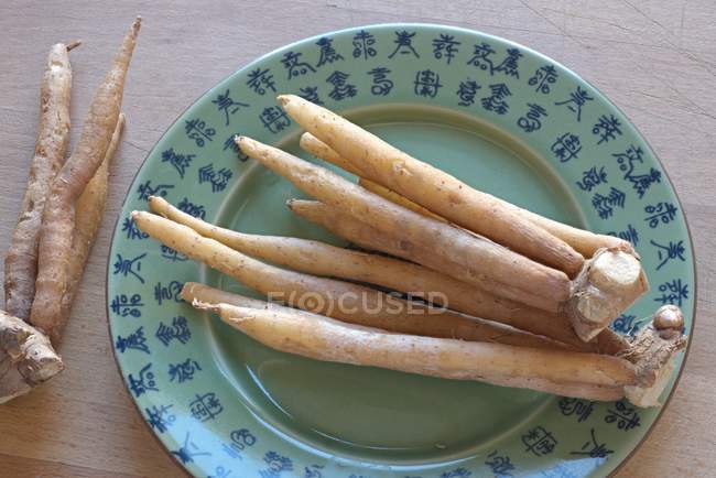 Closeup view of Krachai roots on plate with Asian characters — Stock Photo
