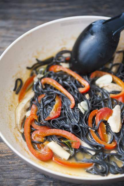 Black linguine pasta with mushrooms and peppers — Stock Photo