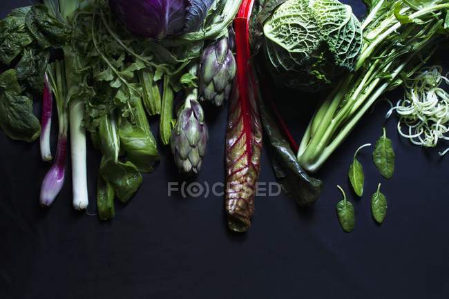 Verduras surtidas sobre una superficie negra - foto de stock