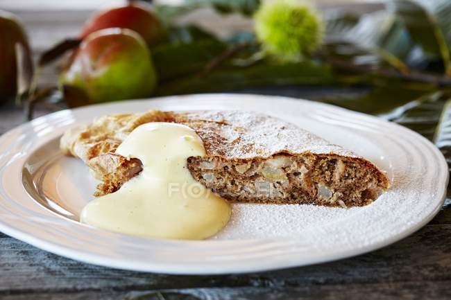 Pear and nut studel with zabaione on white plate — Stock Photo