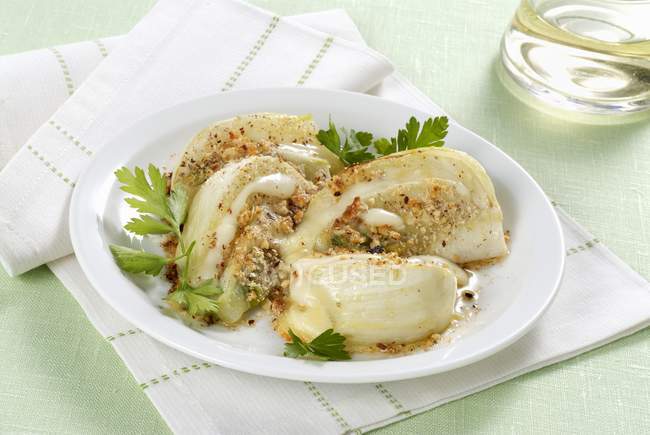 Fennel gratin with hazelnuts  on white plate  over towel — Stock Photo