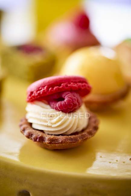 Vista close-up de petit quatro com um macaron e framboesas em um buffet de casamento — Fotografia de Stock
