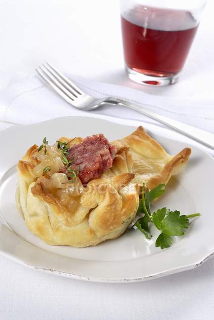 Zampone e pere in cestino - колбаса и груша, завернутые в слоеное тесто на белой тарелке — стоковое фото