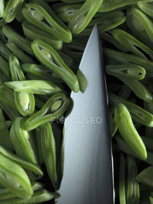 Ponta de uma faca com verde fatiado no fundo preto — Fotografia de Stock