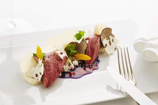 Piccione con tartufo e cavolo rosso su piatto bianco con forchetta e coltello — Foto stock