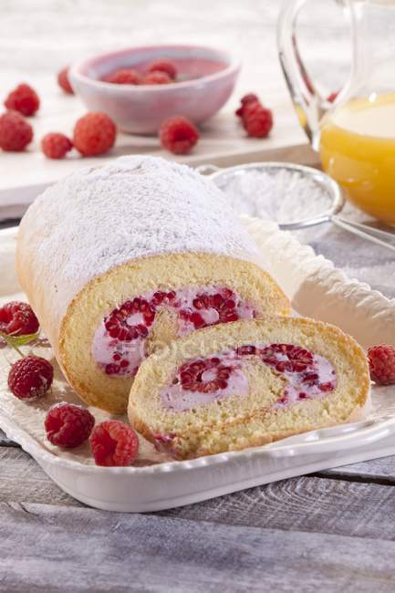 Closeup view of Swiss roll with raspberries and icing sugar — Stock Photo