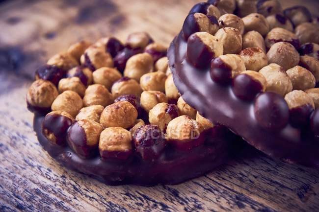 Closeup view of hazelnuts in chocolate on wooden surface — Stock Photo