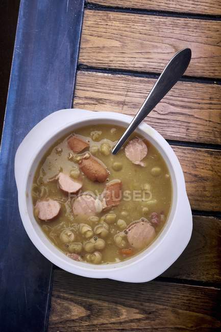 Pea soup with Bockwurst sausage in bowl with spoon — Stock Photo