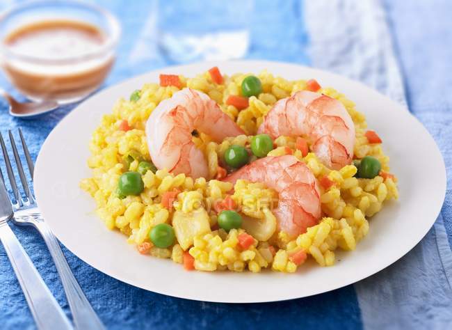 Prawn and pea risotto on white plate over blue surface — Stock Photo