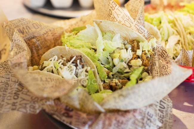 Vue rapprochée des tacos à emporter dans des feuilles de papier — Photo de stock