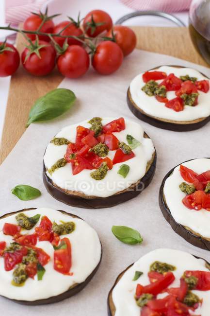 Aubergine pizzettes with tomato and pesto on paper — Stock Photo
