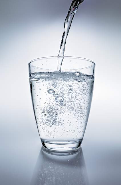 Vue rapprochée de verser de l'eau sur le verre — Photo de stock