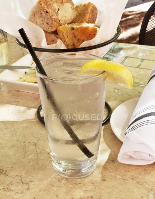 A glass of ice water with a slice of lemon at a restaurant — Stock Photo