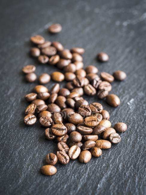 Кофейные зерна на темной поверхности — стоковое фото