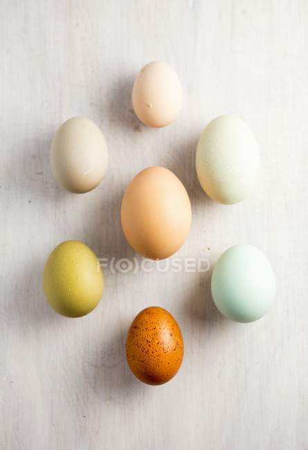 Vista superior de cerca de varios huevos de colores en la superficie blanca - foto de stock