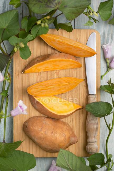 Süßkartoffel in Scheiben geschnitten mit Blättern und Blüten — Stockfoto