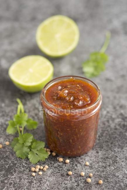 Closeup view of halved lime with mango, chilli and coriander chutney in a glass jar — Stock Photo
