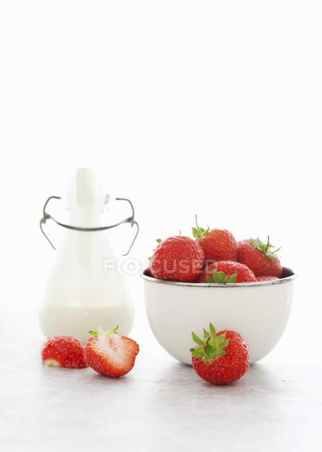 Fresh strawberries and bottle of cream — Stock Photo