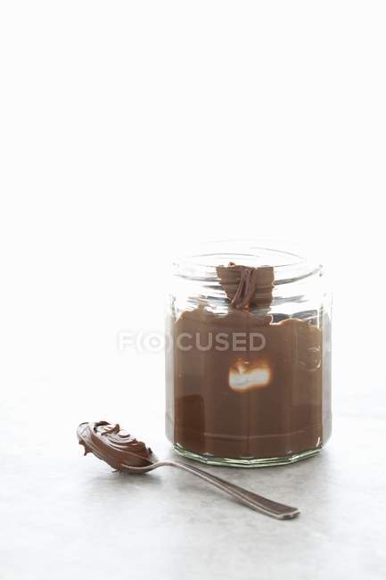 Closeup view of chocolate butter in jar and on spoon — Stock Photo