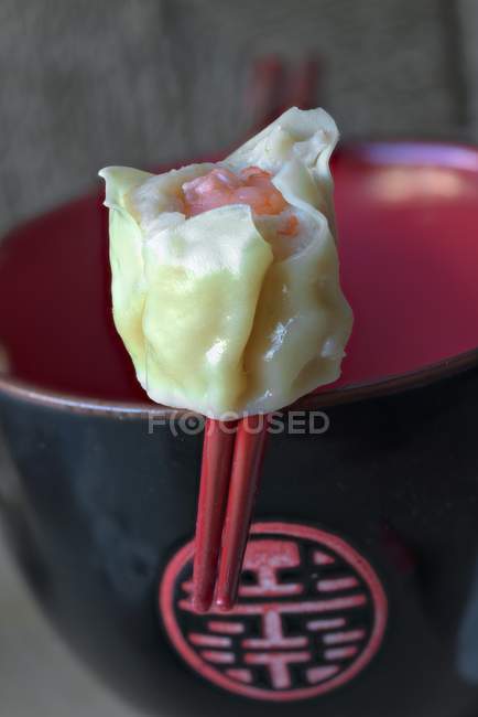 Closeup view of Asian Dim Sum on red chopsticks — Stock Photo