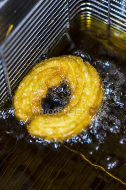 Closeup view of Churro in a deep fat fryer with oil — Stock Photo