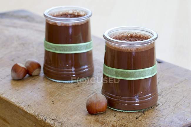 Vista de primer plano de flan de chocolate y avellana en vasos - foto de stock