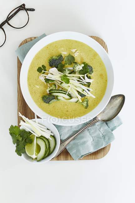 Curry with broccoli and cucumber on white plate over wooden desk with spoon — Stock Photo