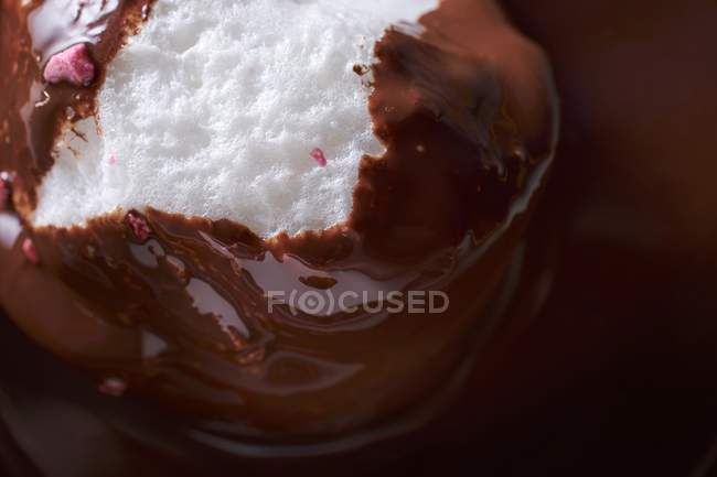 Closeup view of floating cream island in chocolate sauce — Stock Photo