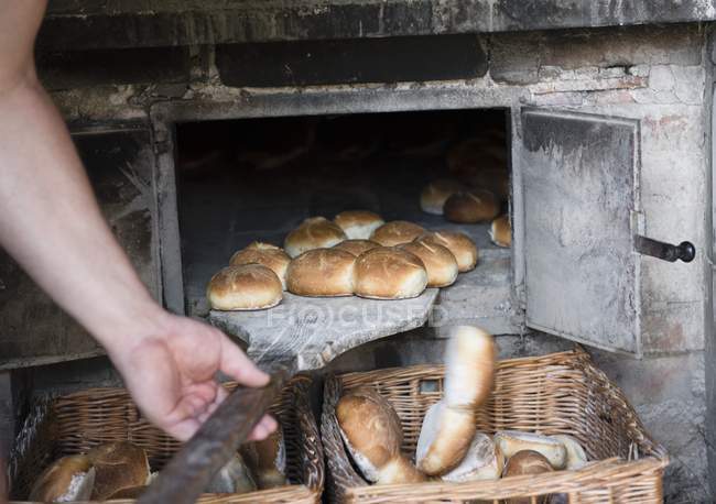 Чоловік ковзає хлібні рулони — стокове фото