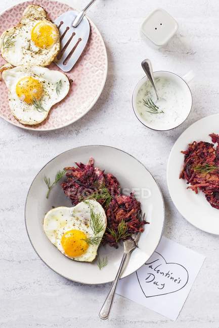 Beetroot and  carrot fritters wth heart-shaped fried eggs for Valentine's Day — Stock Photo