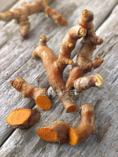Vista close-up de raízes de cúrcuma frescas em uma superfície de madeira — Fotografia de Stock