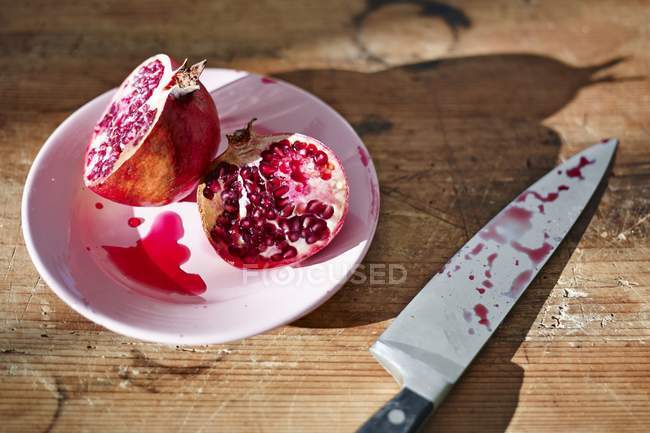 Halved pomegranate in pink plate — Stock Photo