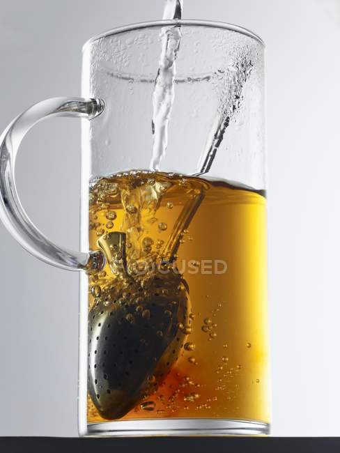 Assam tea in glass with tea infuser — Stock Photo