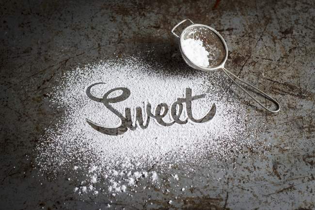 Close-up vista da palavra Doce escrito em açúcar de confeiteiro — Fotografia de Stock
