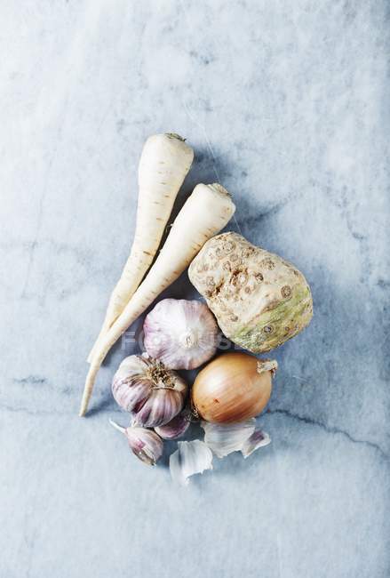 Сельдерей, петрушка, чеснок и лук на мраморном фоне — стоковое фото