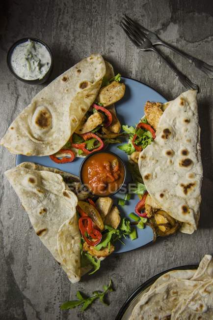 Draufsicht auf Tortilla-Wraps mit Gewürzhuhn, Zwiebeln, Paprika, Salsa und einem Joghurt-Dip — Stockfoto