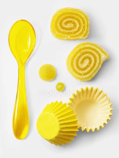Vista de primer plano de caramelos laminados amarillos y vasos de papel por cuchara - foto de stock