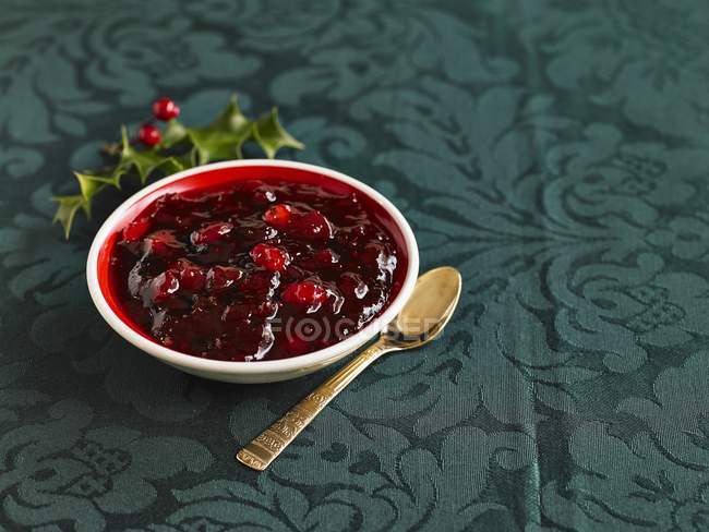 Closeup view of cranberry sauce in bowl and spoon — Stock Photo