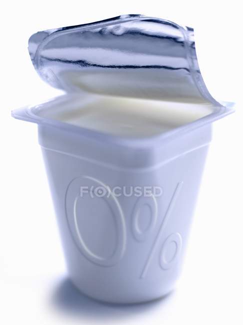 Envase abierto de yogur simple con cero por ciento de grasas - foto de stock