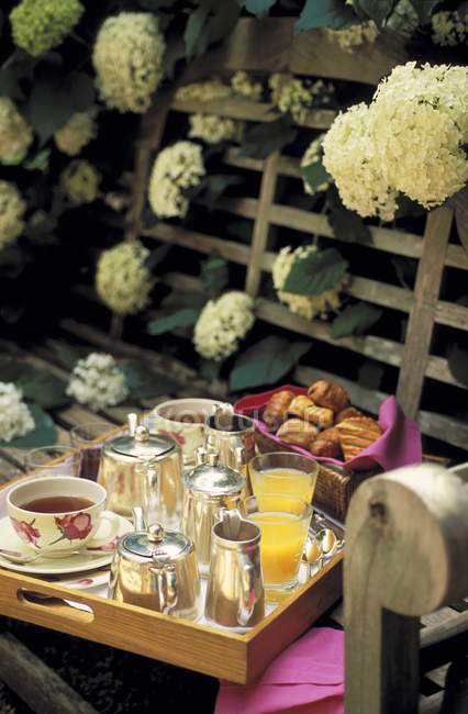 Daytime view of breakfast tray on a wooden bench with white flowers — Stock Photo