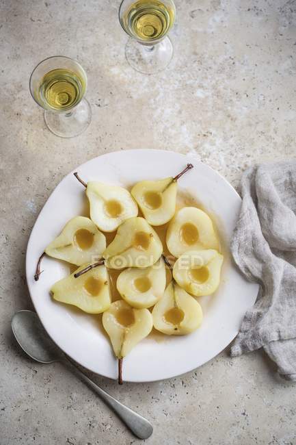 Top view of poached pear halves on white plate with drinks — Stock Photo