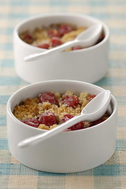Closeup view of cherry crumbles with spoons in bowls — Stock Photo