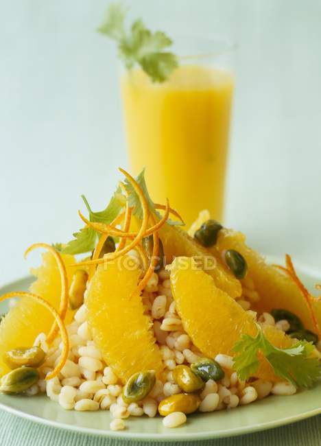 Wheat with oranges and pistachios on green plate — Stock Photo