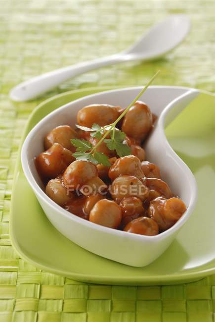 Pilze la Grecque in weißer Schüssel über grünem Teller auf Tisch mit weißem Löffel — Stockfoto