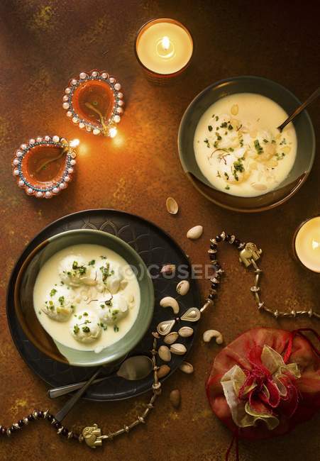 Vista superior de sobremesas indianas Ras malai com nozes e velas acesas — Fotografia de Stock