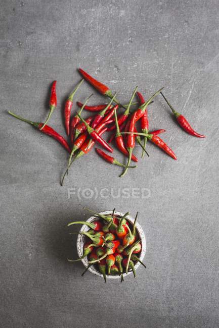 Bowl of chillis and scattered chillis — Stock Photo