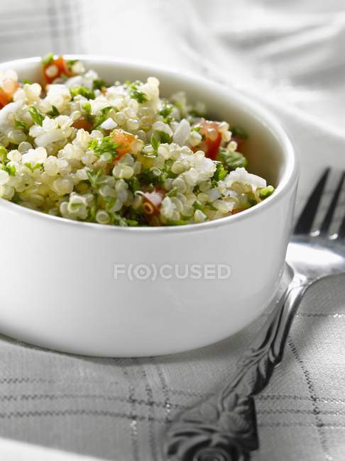 Taboulé de quinoa dans un plat blanc sur une serviette avec fourchette — Photo de stock
