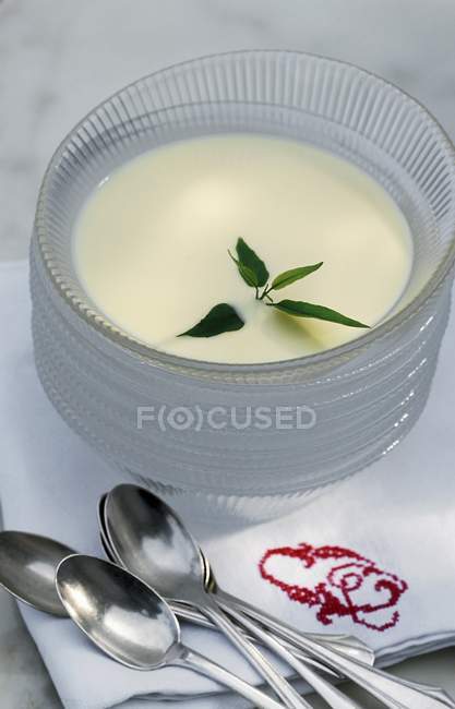Vue rapprochée de la crème anglaise avec des herbes dans des bols en verre empilés — Photo de stock